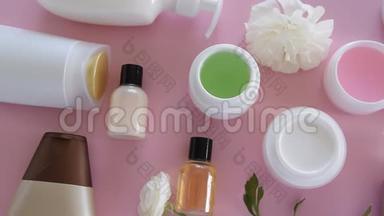 在新鲜的粉红色背景下，可以看到不同的卫生/化妆品产品和鲜花。 健康美容治疗